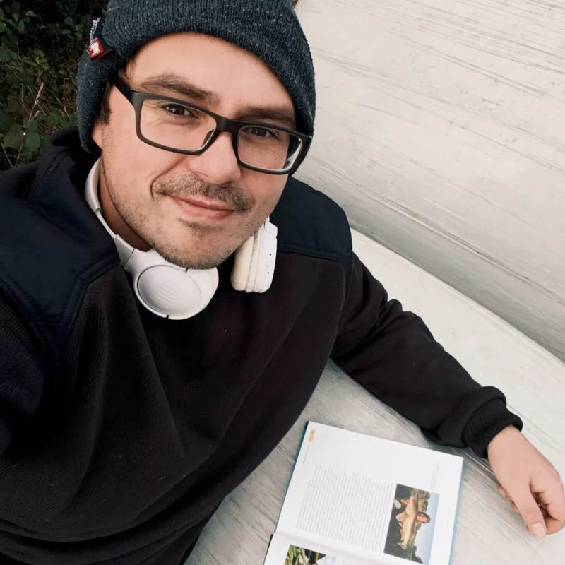Christoph liegt auf einem Holzballen und liest ein Buch aus seiner Angelbuchsammlung