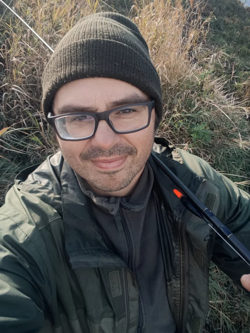 Christoph mit Regenjacke, Mütze und Matchrute beim Angeln im Oktober