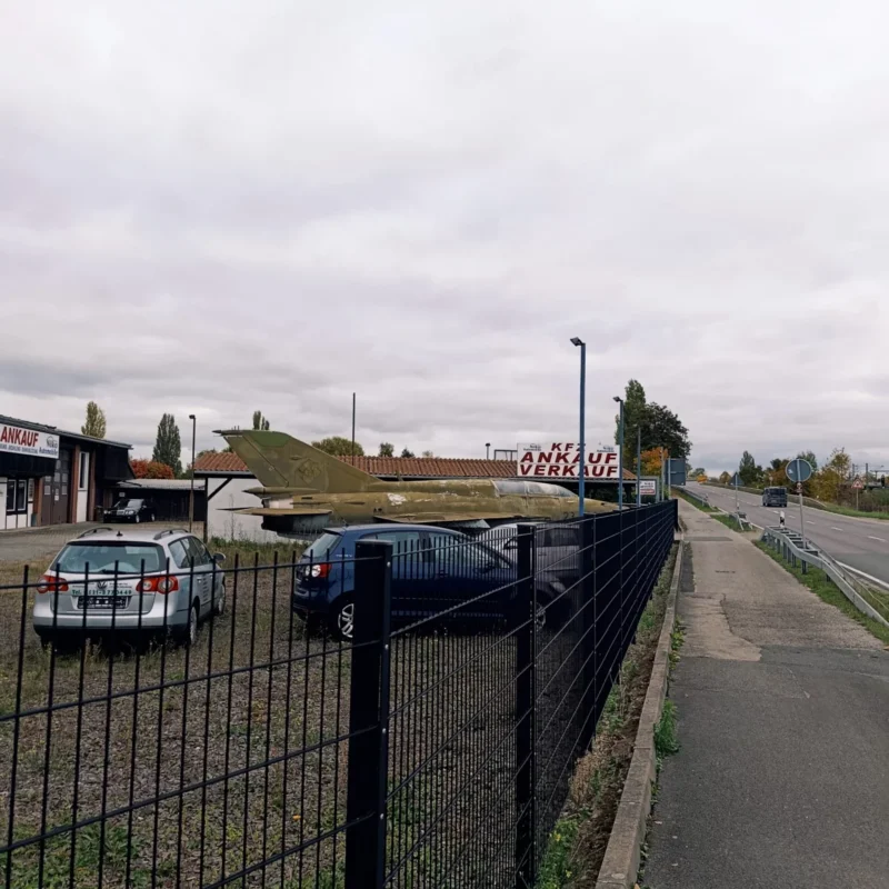 ein altes Flugzeug, das auf dem Parkplatz eines Gebrauchtwagenhändlers steht