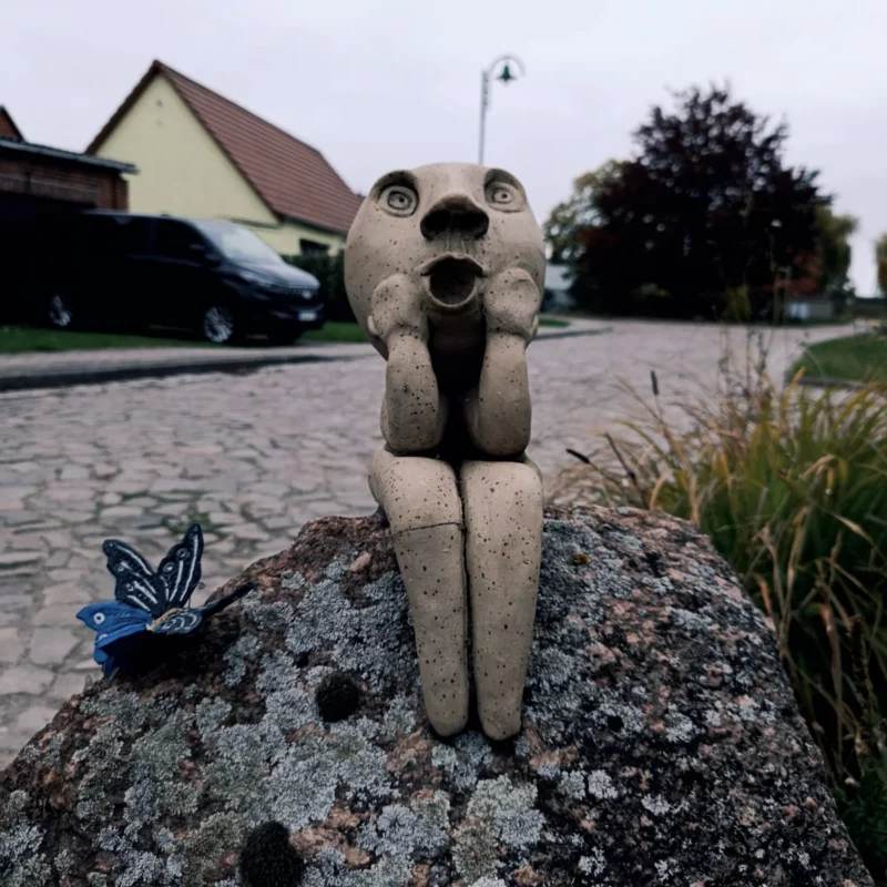 Kunstfigur auf einem Grundstücksstein