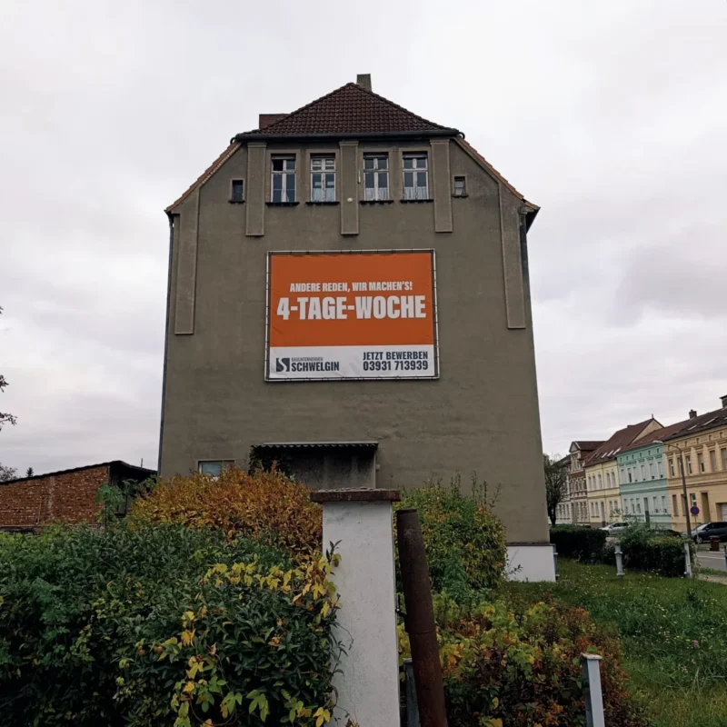 Reklame für die 4 Tage Woche an einer alten Hauswand