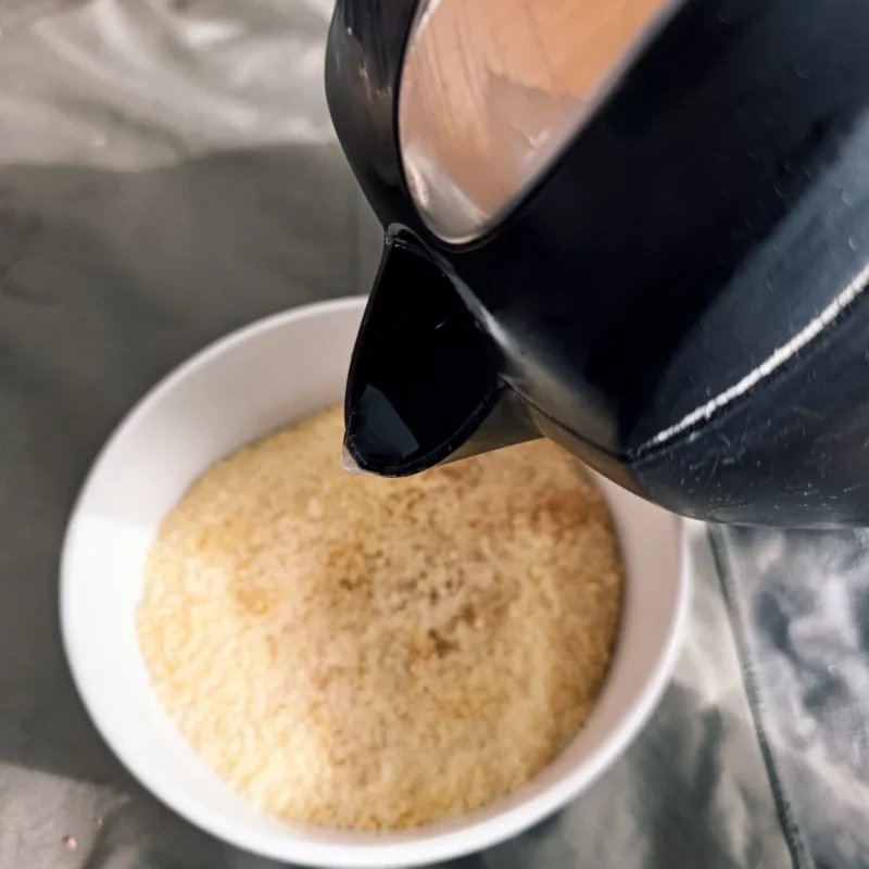 Couscous und Maggi werden in einer Schale mit kochendem Wasser angesetzt 