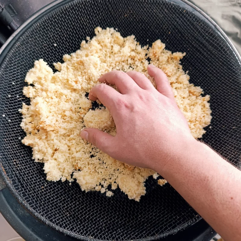 Maggi Couscous Futterpartikel für Rotaugen wird durch einen Sieb gerieben