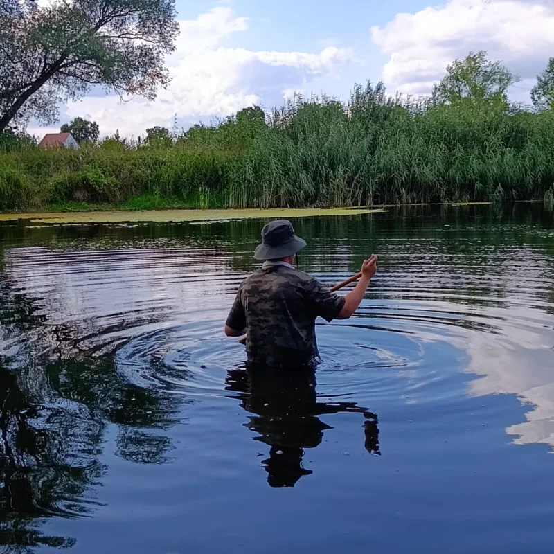 Angler beim Freiharken von Kraut am Teich für eine freie Angelstelle
