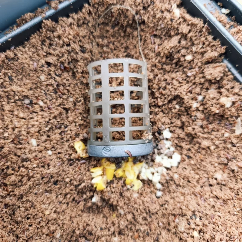 Futterkorb mit Ködern und Futter zum Anfüttern für Rotaugen im Oktober am Teich